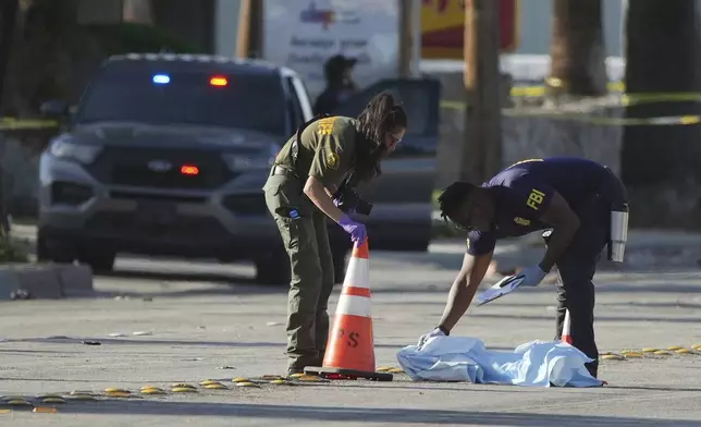 Investigators place a tarp over an item on a road near the site of an explosion in Palm Springs, Calif., on Saturday, May 17, 2025. (AP Photo/Eric Thayer)