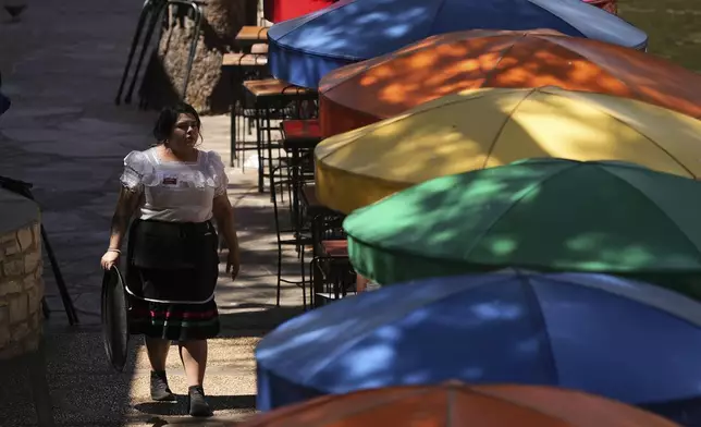 A waitress tends to outdoor patrons as temperatures top the triple-digit mark, Tuesday, May 13, 2025, in San Antonio. (AP Photo/Eric Gay)