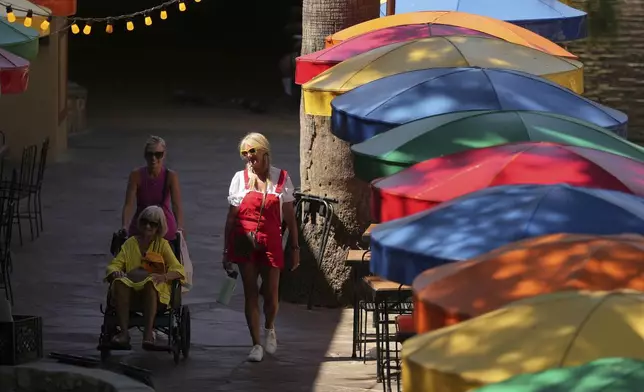 Visitors walk along the River Walk as temperatures top the triple-digit mark, Tuesday, May 13, 2025, in San Antonio. (AP Photo/Eric Gay)