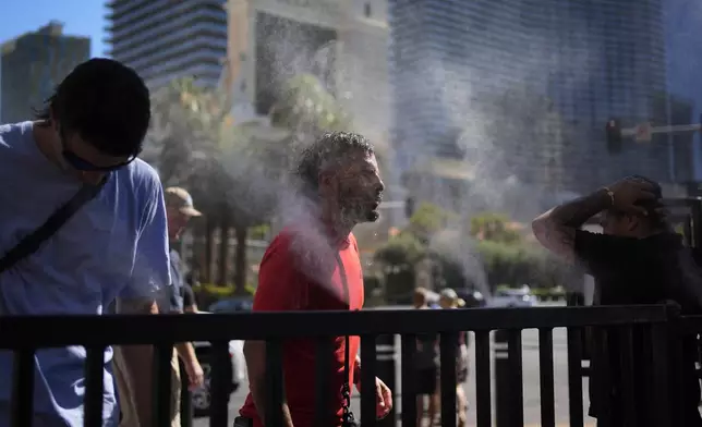 FILE - People cool off in misters during a heat wave along the Las Vegas Strip, Sunday, July 7, 2024, in Las Vegas. (AP Photo/John Locher, file)