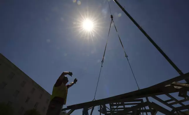 A construction worker guides a crane as temperatures top the triple-digit mark, Tuesday, May 13, 2025, in San Antonio. (AP Photo/Eric Gay)