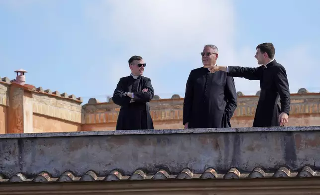 Priests standing on a terrace look at St. Peter's Square, at the Vatican, Wednesday, May 7, 2025. (AP Photo/Gregorio Borgia)