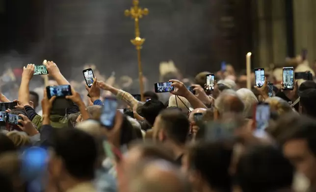 Faithful capture images with their smartphones of cardinals during a final Mass inside St. Peter's Basilica before the conclave to elect a new pope, at the Vatican, Wednesday, May 7, 2025. (AP Photo/Gregorio Borgia)