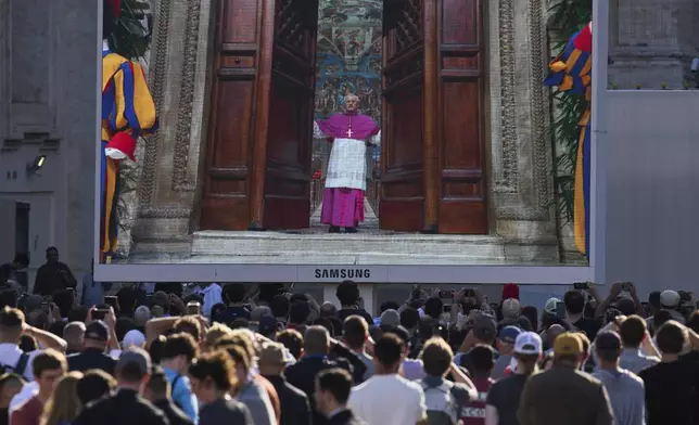 A giant screen in St Peter's Basilica shows a Vatican official closing the door to the Sistine Chapel after calling out "extra omnes", Latin for "all out", during the cardinals' conclave to elect a new pope, at the Vatican, Wednesday, May 7, 2025. (AP Photo/Bernat Armangue)