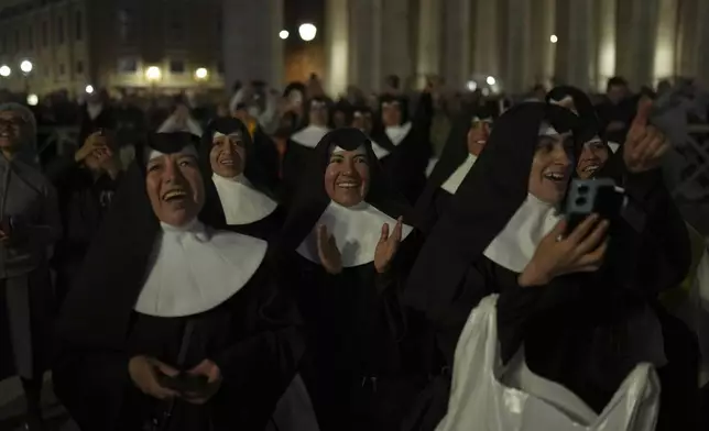 Nuns applaud as black smoke billows from the chimney of the Sistine Chapel during the cardinals' conclave to elect a new pope, at the Vatican, Wednesday, May 7, 2025. (AP Photo/Francisco Seco)