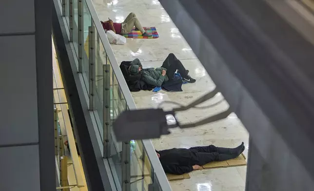 People sleep on the floor of Terminal 4 at Adolfo Suarez-Madrid Barajas Airport in Madrid, Spain, Thursday, May 15, 2025. (AP Photo/Manu Fernandez)