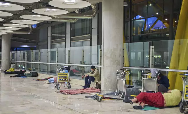 People sleep on the floor of Terminal 4 at Adolfo Suarez-Madrid Barajas Airport in Madrid, Spain, Thursday, May 15, 2025. (AP Photo/Manu Fernandez)