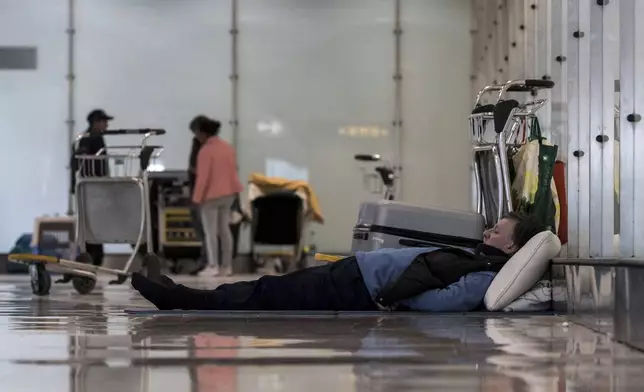 A person sleeps on the floor of Terminal 4 at Adolfo Suárez-Madrid Barajas Airport in Madrid, Spain, Monday, May 12, 2025. (Diego Radames/Europa Press via AP)