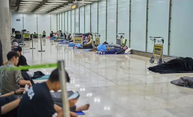 People sleep on the floor of Terminal 4 at Adolfo Suarez-Madrid Barajas Airport in Madrid, Spain, Thursday, May 15, 2025. (AP Photo/Manu Fernandez)