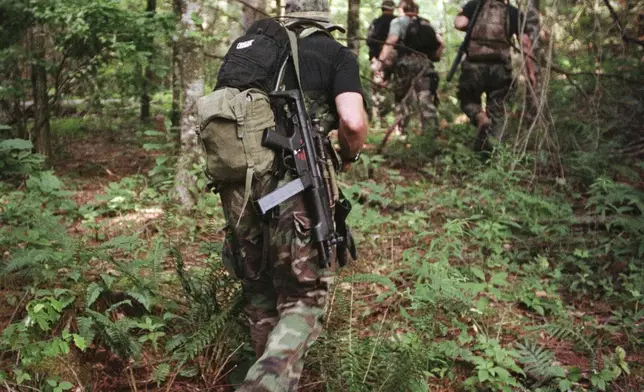 FILE - An armed search team enters the forest near Nantahala, N.C., July 16, 1998, as authorities continue their search for bombing suspect Eric Rudolph. (AP Photo/Alan Marler, File)