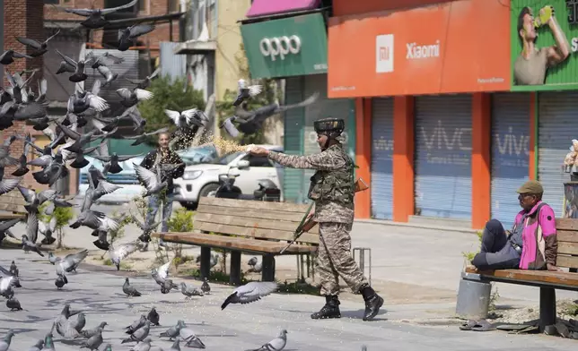 An Indian soldier feeds pigeons at a market, day after India and Pakistan agreed to a ceasefire Saturday following U.S.-led talks to end the most serious military confrontation between the nuclear-armed rivals in decades, in Srinagar, in Indian controlled Kashmir, Sunday, May 11, 2025.(AP Photo/Mukhtar Khan)