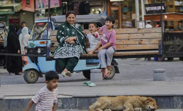 A Kashmiri woman along with her children sits on a swing after ceasefire between India and Pakistan was announced in Srinagar, in Indian controlled Kashmir, Saturday, May 10, 2025.(AP Photo/Mukhtar Khan)