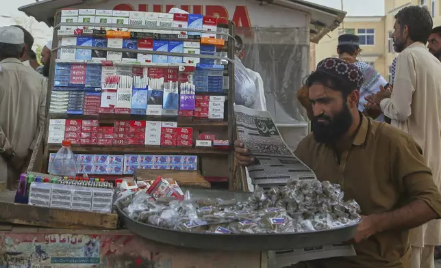 A street hawker reads a morning newspaper at a stall, a day after the ceasefire between Indian and Pakistan was announced, in Peshawar, Pakistan, Sunday, May 11, 2025. (AP Photo/Muhammad Sajjad)