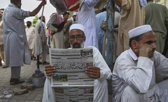 A Pakistani reads a morning newspaper at a stall, a day after the ceasefire between Indian and Pakistan was announced, in Peshawar, Pakistan, Sunday, May 11, 2025. (AP Photo/Muhammad Sajjad)