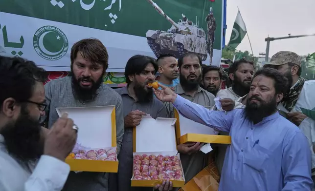 People share sweets as they celebrate following India and Pakistan have reached a ceasefire deal, during a demonstration, in Lahore, Pakistan, Saturday, May 10, 2025. (AP Photo/K.M. Chaudary)