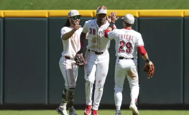 Cincinnati Reds' Will Benson (30) celebrates with teammates Connor Joe (17) and TJ Friedl (29) following a baseball game against the Cleveland Guardians, Sunday, May 18, 2025, in Cincinnati. (AP Photo/Jeff Dean)