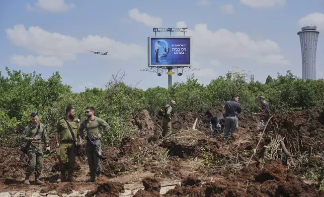 Israeli security forces inspect the site where the Israeli military said a projectile fired by Yemen's Houthi rebels landed in the area of Ben Gurion International Airport near Tel Aviv, Israel, on Sunday, May 4, 2025. (AP Photo/Ohad Zwigenberg)