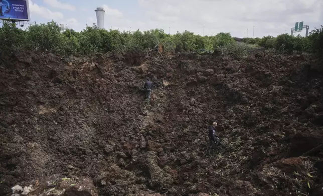 Israeli security forces inspect a crater at the site where the Israeli military said a projectile fired by Yemen's Houthi rebels landed in the area of Ben Gurion International Airport near Tel Aviv, Israel, on Sunday, May 4, 2025. (AP Photo/Ohad Zwigenberg)