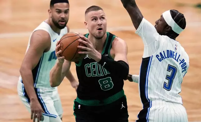 Boston Celtics center Kristaps Porzingis (8) drives to the basket against Orlando Magic guard Kentavious Caldwell-Pope (3) during the first half in game 5 of a first-round NBA playoff basketball series, Tuesday, April 29, 2025, in Boston. (AP Photo/Charles Krupa)