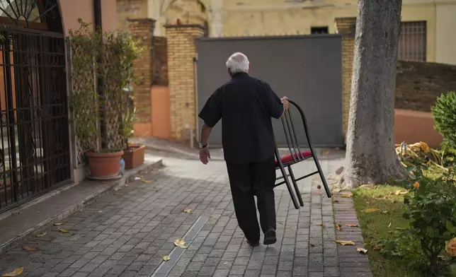 Guatemalan Cardinal Alvaro Ramazzini carries the chair he sat on, at the end of an interview with the Associated Press at the headquarters of the Scalabrinian congregation, in Rome, Saturday, May 3, 2025. (AP Photo/Francisco Seco)