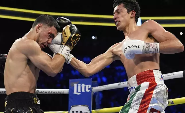 Rafael Espinoza hits Edward Vazquez in a featherweight title boxing match Sunday, May 4, 2025, in Las Vegas. (AP Photo/John Locher)