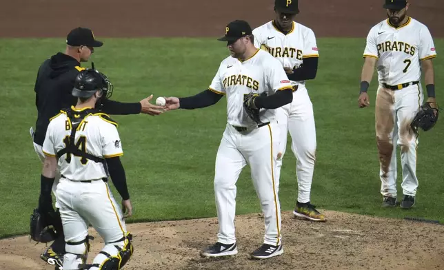 Pittsburgh Pirates pitcher David Bednar, center, hands the baseball to manager Don Kelly, left rear, during the eighth inning of a baseball game in Pittsburgh, Monday, May 19, 2025. (AP Photo/Gene J. Puskar)