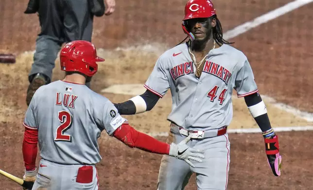 Cincinnati Reds' Elly De La Cruz (44) is greeted by Gavin Lux as he returns to the dugout after scoring from third on a single by Austin Hays off Pittsburgh Pirates pitcher David Bednar during the eighth inning of a baseball game in Pittsburgh, Monday, May 19, 2025. (AP Photo/Gene J. Puskar)
