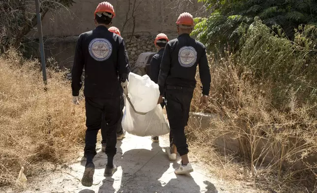 FILE - First responders carry a body at the site of a mass grave in Raqqa, Syria, the city that served as the de facto capital of the Islamic State group, Sept. 7, 2019. (AP Photo/Maya Alleruzzo, File)