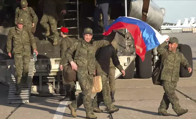In this photo taken from video released by Russian Defense Ministry Press Service on Saturday, May 24, 2025, Russian servicemen leave a plane upon arrival to Chkalovsky airport, outside Moscow, Russia, after returning from captivity by a POWs exchange between Russia and Ukraine. (Russian Defense Ministry Press Service photo via AP)