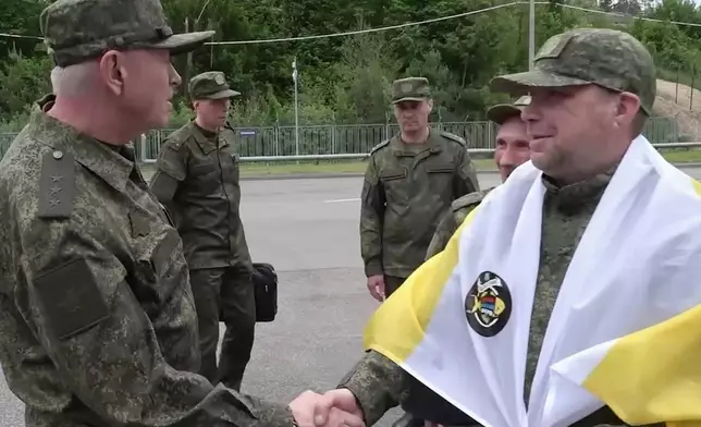 In this photo taken from a video released by Russian Defense Ministry press service, a Russian serviceman, right, speaks on the phone after returning from captivity after an exchange between Russia and Ukraine, at an undisclosed location in Belarus, Saturday, May 24, 2025. (Russian Defense Ministry Press Service via AP)