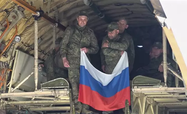 In this photo taken from video released by Russian Defense Ministry Press Service on Saturday, May 24, 2025, Russian servicemen hold a Russian flag upon arrival to Chkalovsky airport, outside Moscow, Russia, after returning from captivity by a POWs exchange between Russia and Ukraine. (Russian Defense Ministry Press Service photo via AP)