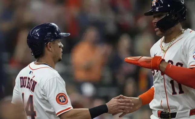 Houston Astros' Mauricio Dubon (14) celebrates with Cam Smith (11) after they both scored off of a triple by Jeremy Peña during the fourth inning of a baseball game against the Seattle Mariners in Houston, Thursday, May 22, 2025. (AP Photo/Ashley Landis)