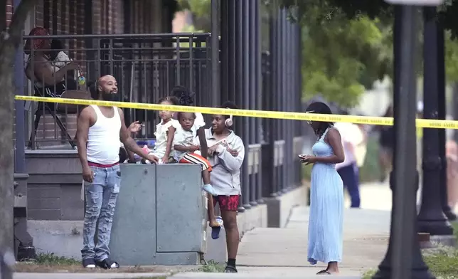 Residents watch as police pursue a fugitive that escaped from a New Orleans jail, Tuesday, May 20, 2025, in New Orleans. (AP Photo/Gerald Herbert)