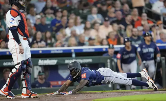 Seattle Mariners' Randy Arozarena (56) scores as Houston Astros catcher Victor Caratini stands at home plate during the second inning of a baseball game Saturday, May 24, 2025, in Houston. (AP Photo/David J. Phillip)