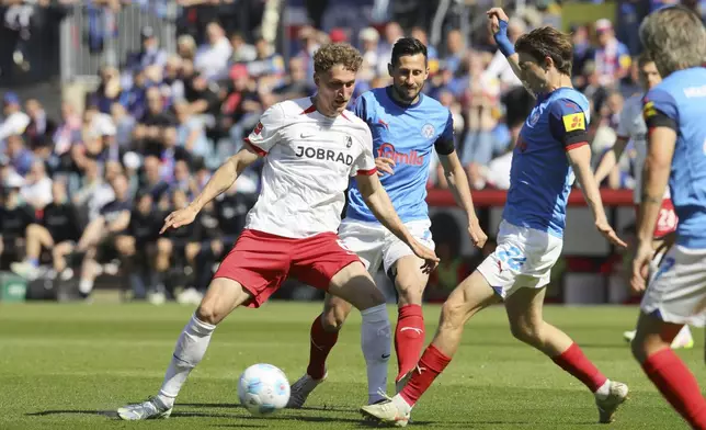 Freiburg's Magnus Knudsen, right, and Kiel's Steven Skrzybski, second right, challenge for the ball during the German Bundesliga soccer match between Holstein Kiel and SC Freiburg in Kiel, Germany, Saturday, May 10, 2025. (Claus Bergmann/dpa via AP)