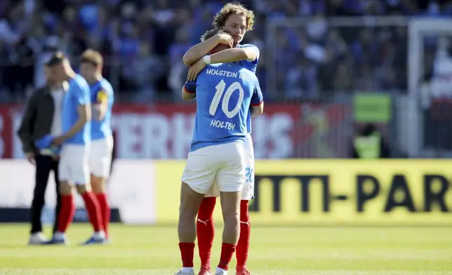 Kiel's Lewis Holtby is comforted by Fiete Arp after the German Bundesliga soccer match between Holstein Kiel and SC Freiburg in Kiel, Germany, Saturday, May 10, 2025. (Claus Bergmann/dpa via AP)