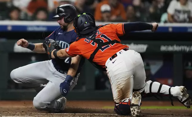 Houston Astros catcher Yainer Diaz (21) tags out Seattle Mariners' Cal Raleigh at home plate during the sixth inning of a baseball game in Houston, Friday, May 23, 2025. (AP Photo/Ashley Landis)