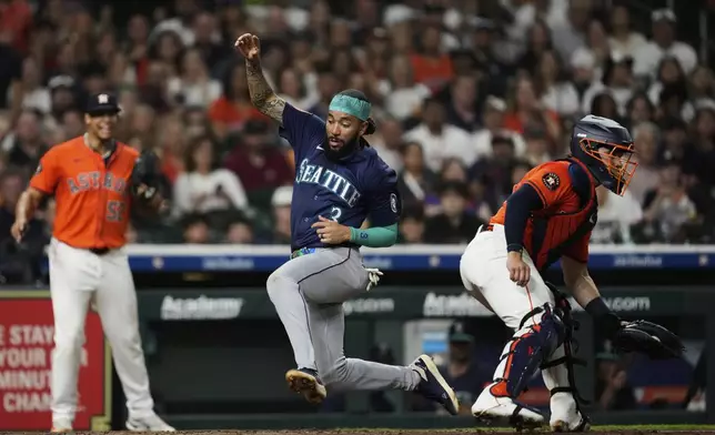 Seattle Mariners' J.P. Crawford (3) scores ahead of a throw to Houston Astros catcher Yainer Diaz, right, during the seventh inning of a baseball game in Houston, Friday, May 23, 2025. (AP Photo/Ashley Landis)
