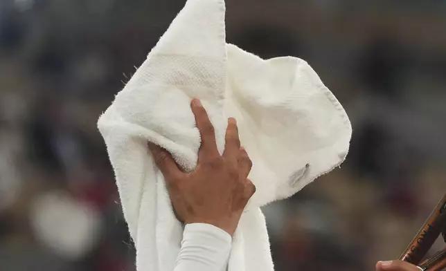 China's Zheng Qinwen wipes her face as she plays Russia's Anastasia Pavliuchenkova during their first round match of the French Tennis Open at the Roland Garros stadium, in Paris, Sunday May 25, 2025. (AP Photo/Lindsey Wasson)