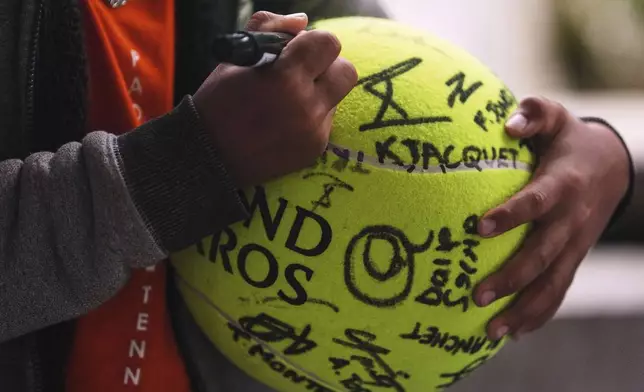 A fan signs a large tennis ball at the Roland Garros stadium ahead of the French Open tennis tournament, Saturday May 24, 2025 in Paris. (AP Photo/Lindsey Wasson)