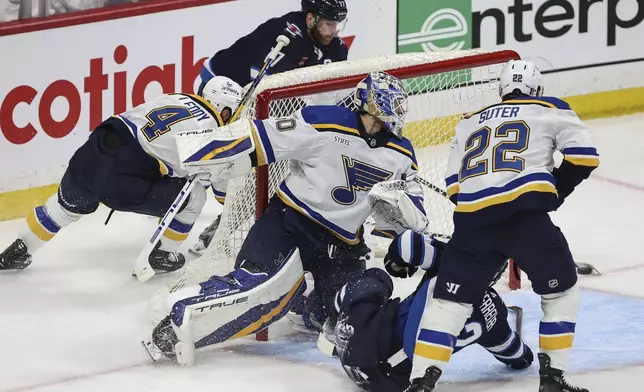 Winnipeg Jets' Adam Lowry (17) attempts a wraparound as Nino Niederreiter (62) crashes into St. Louis Blues goaltender Jordan Binnington (50) and Ryan Suter (22) defends during the third period of an NHL playoff game in Winnipeg on Wednesday, April 30, 2025. (John Woods/The Canadian Press via AP)