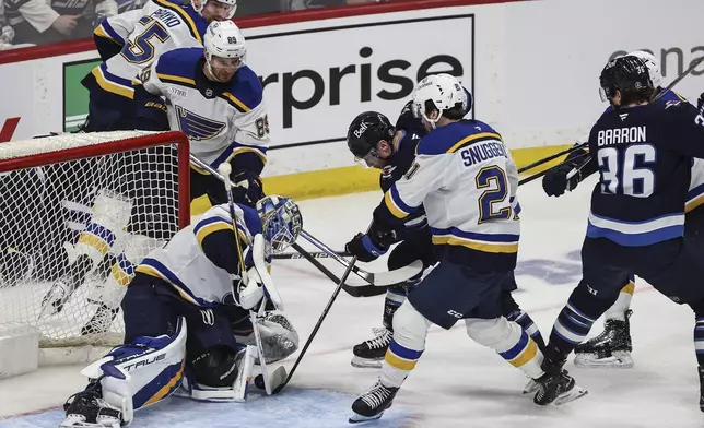 St. Louis Blues goaltender Jordan Binnington (50) saves the shot from Winnipeg Jets' Jaret Anderson-Dolan (28) during first period NHL playoff action in Winnipeg on Wednesday, April 30, 2025. (John Woods/The Canadian Press via AP)