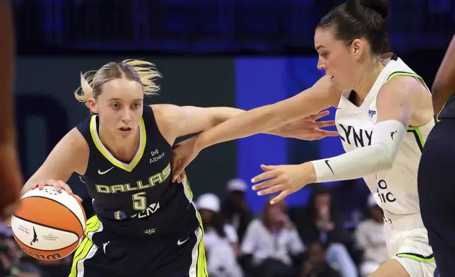 Dallas Wings guard Paige Bueckers (5) drives the ball past Minnesota Lynx forward Bridget Carleton, right, in the first half in a WNBA basketball game Friday, May 16, 2025, in Arlington, Texas. (AP Photo/Richard W. Rodriguez)