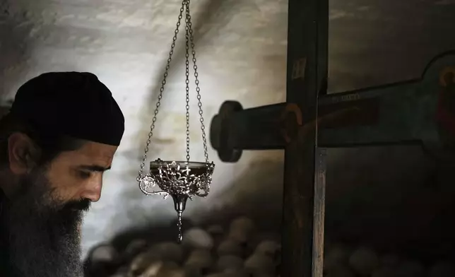 Father Serafeim prays in the ossuary of Simonopetra, or the Simonos Petra Monastery, home of the all-male autonomous community Agion Oros, or Holy Mountain, on the peninsula of Mount Athos in northern Greece, Monday, April 14, 2025. (AP Photo/Thanassis Stavrakis)