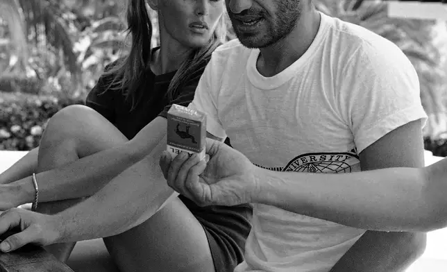 FILE - Accompanied by Swedish Movie star Ursula Andress, French actor Jean Belmondo looks down at a pack of cigarettes being offered to him at their hotel's pool-side bar, April 18, 1967, in Acapulco, Mexico. (AP Photo, File)