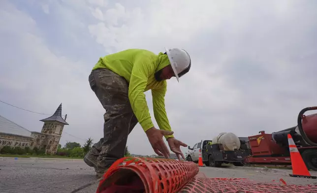 Javier Ortiz rolls up a barrier while laying fiber optic cable in Princeton, Texas, Friday, May 16, 2025. (AP Photo/LM Otero)