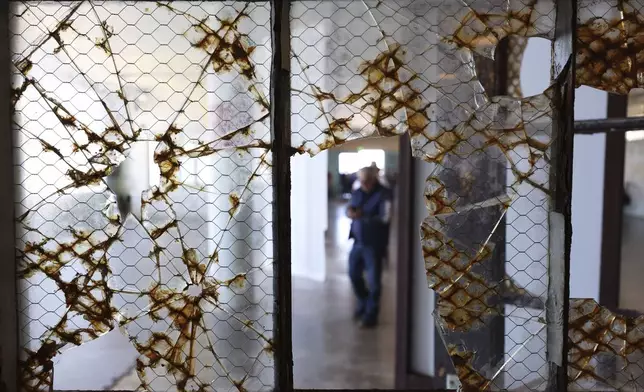 A visitor is framed by broken glass while touring Alcatraz Island in San Francisco, Monday, May 5, 2025. (AP Photo/Jed Jacobsohn)