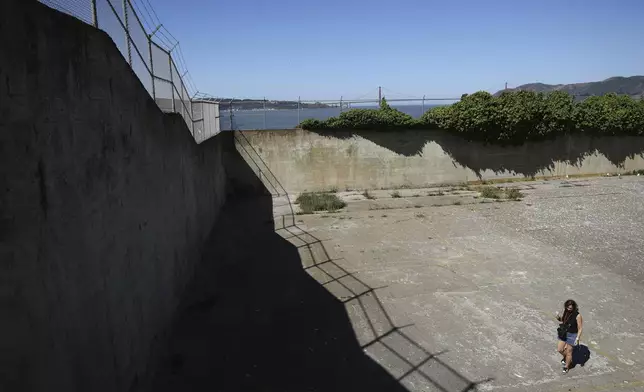 A visitor walks in the recreation yard on Alcatraz Island Monday, May 5, 2025, in San Francisco. (AP Photo/Jed Jacobsohn)