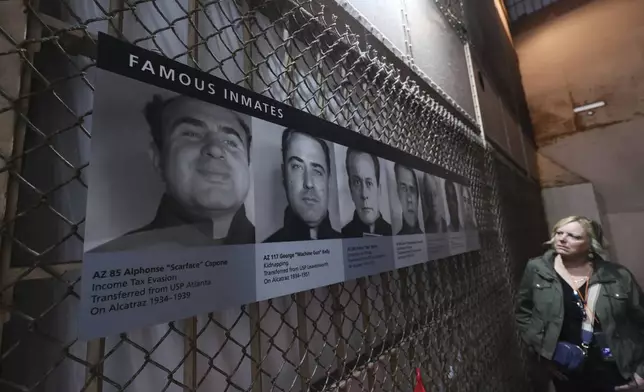 A visitor views pictures of famous inmates on Alcatraz Island Monday, May 5, 2025, in San Francisco. (AP Photo/Jed Jacobsohn)