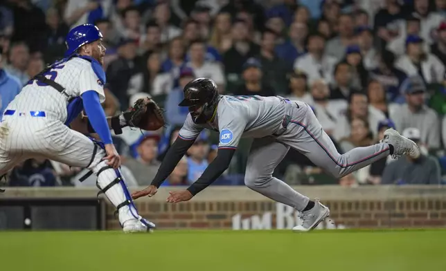 Miami Marlins' Derek Hill (3) dives past Chicago Cubs catcher Carson Kelly (15) to score during the seventh inning of a baseball game Tuesday, May 13, 2025, in Chicago. (AP Photo/Erin Hooley)